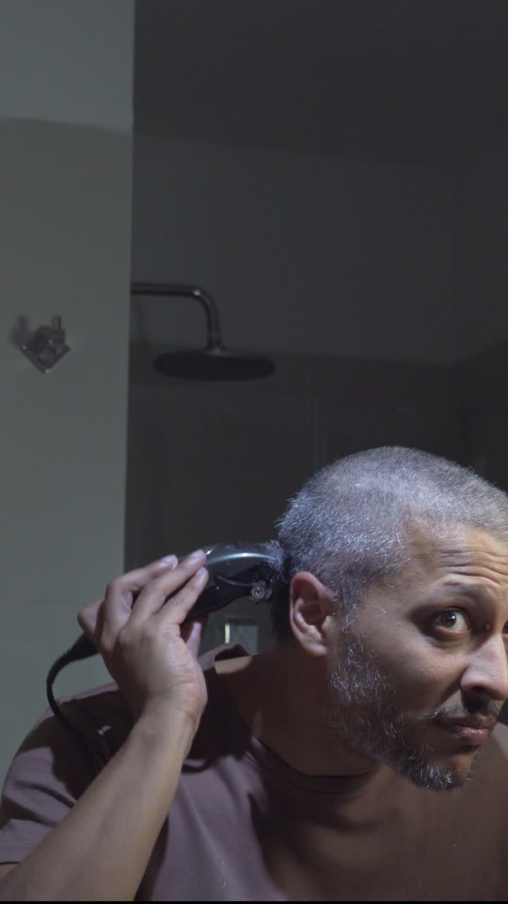 Man Shaving His Head with an Electric Hair Clipper in the Bathroom