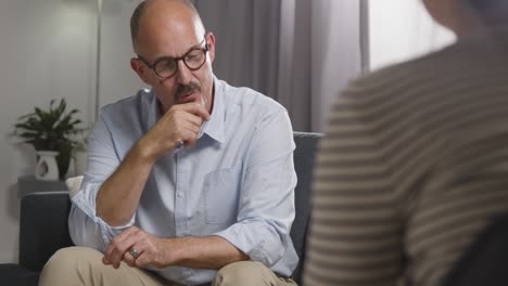 mature man sitting on sofa talking with female counsellor about general or mental health issue 22