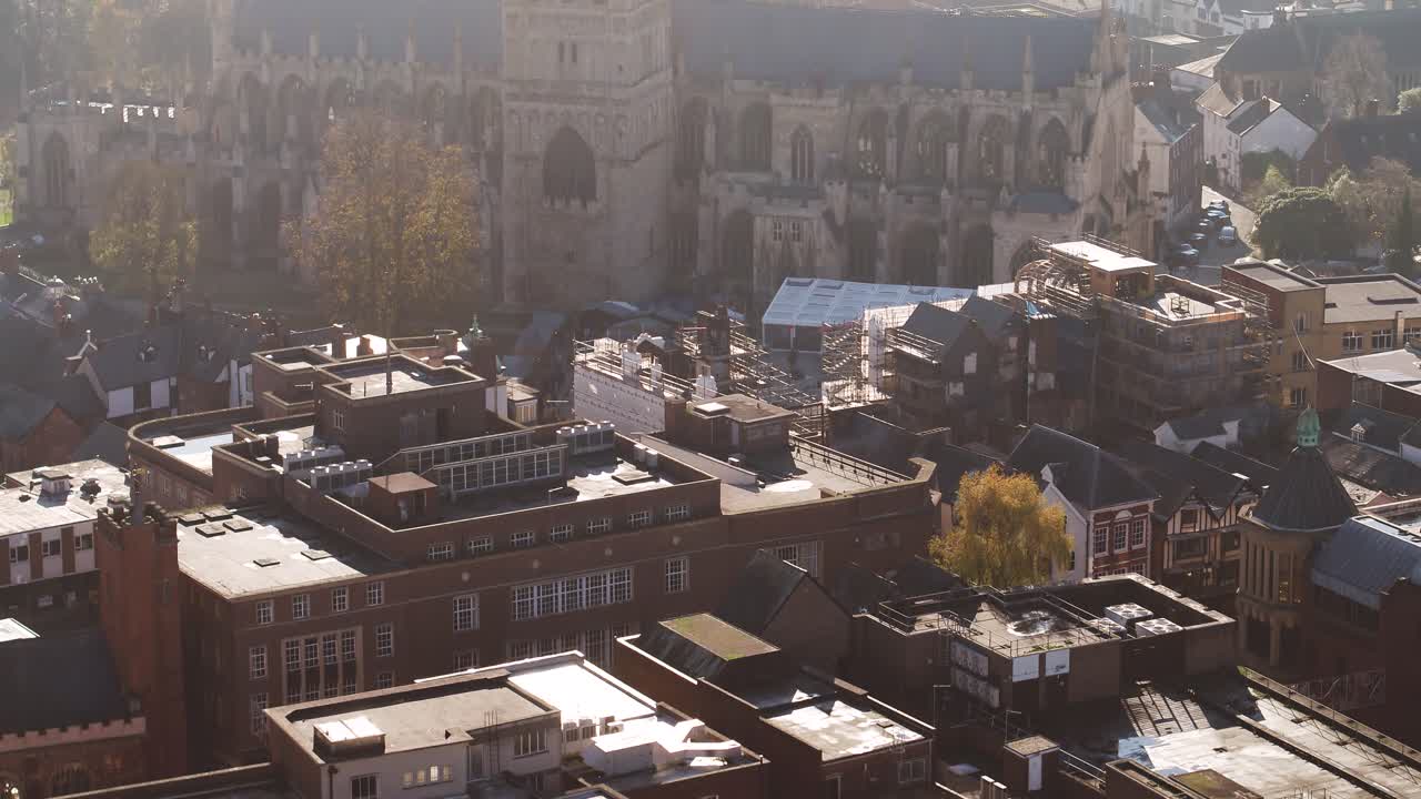 Aerial of the Exeter city rooftops before revealing a glorious cathedral and a river in the hazy distance