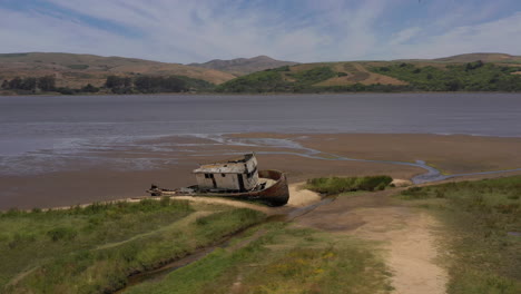 Drone-circling-around-old-shipwreck-at-Point-Reyes,-California,-daytime