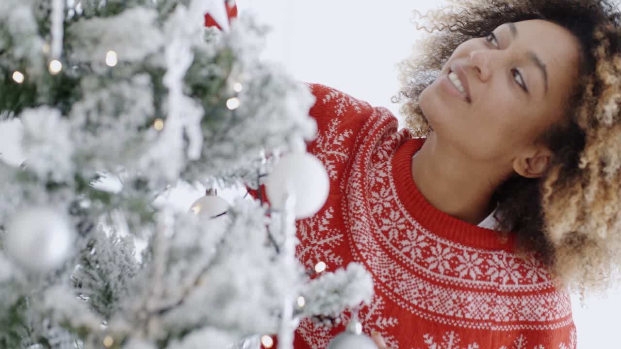 Pretty young woman decorating a Christmas tree