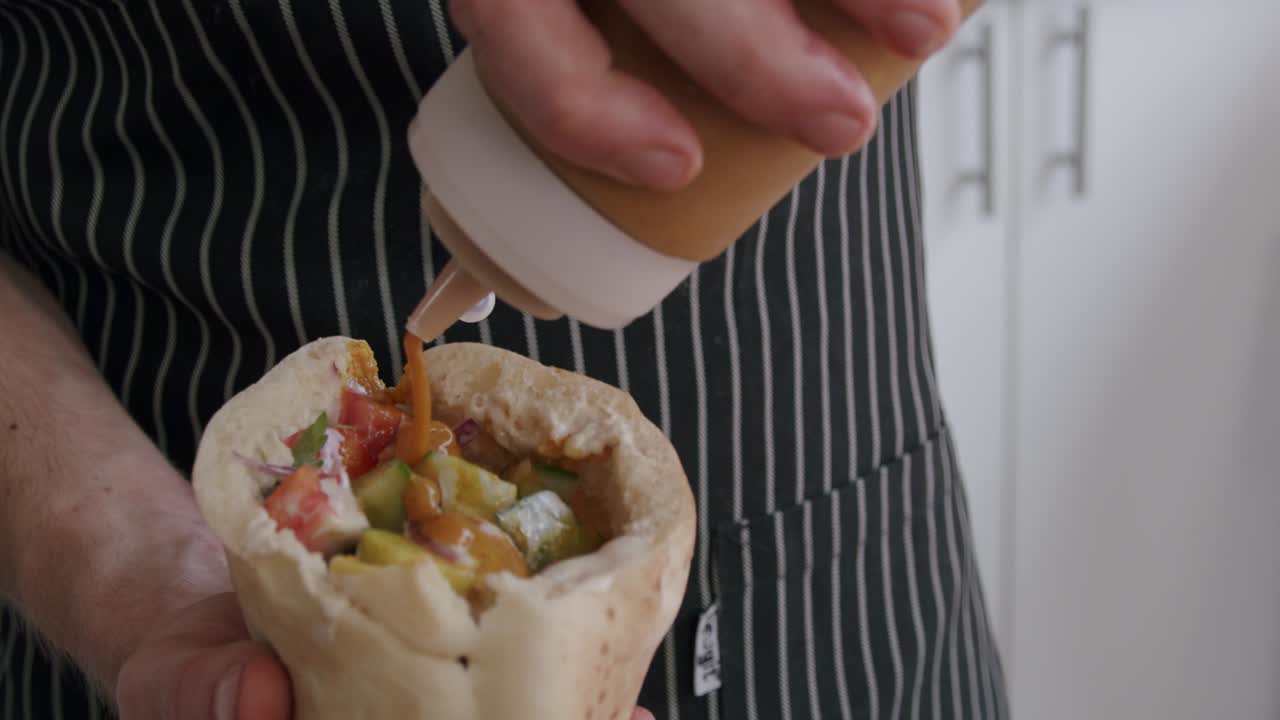 chef condimentando falafel sabich pita comida disparó a 100fps 2