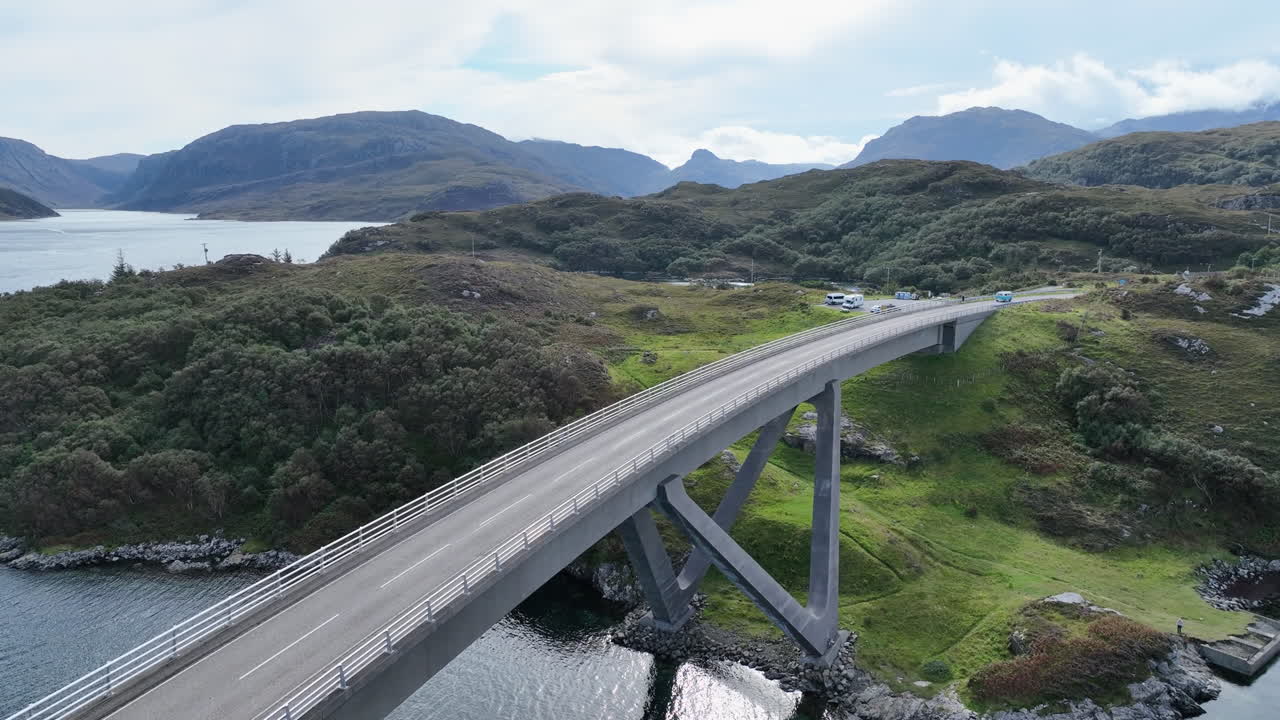Drone footage of Laxford Bridge spanning a tranquil loch surrounded by Highland mountains. Captured along the North Coast 500, showcasing Scotland’s stunning landscape and road architecture