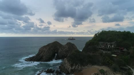 aerial jib up shot from zipolite beach with a big rock formation, oaxaca