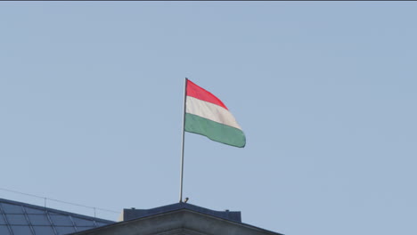 la bandera húngara ondea en lo alto de un edificio histórico en el centro de budapest