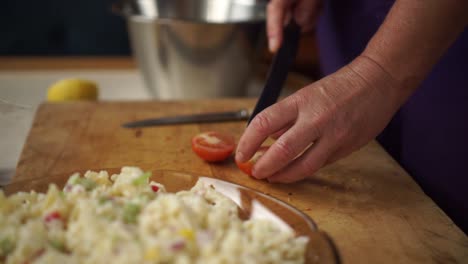 slowmo - elder caucasian woman cuts cherry tomatoes for salad