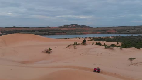 cinematic aerial drone shot following atv quad riding through the sand dunes of vietnam during golden sun rise