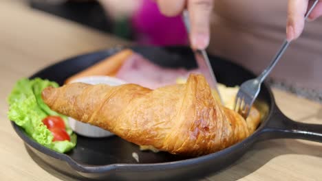cutting and enjoying a croissant breakfast