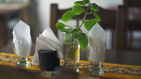 fotografía en primer plano de la mesa de comedor con servilletas, tela estampada y hojas de menta decorativas en un restaurante de campo