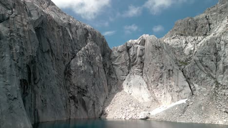 Drone-landing-on-a-remote-blue-lagoon-with-granite-big-walls-on-the-surroundings