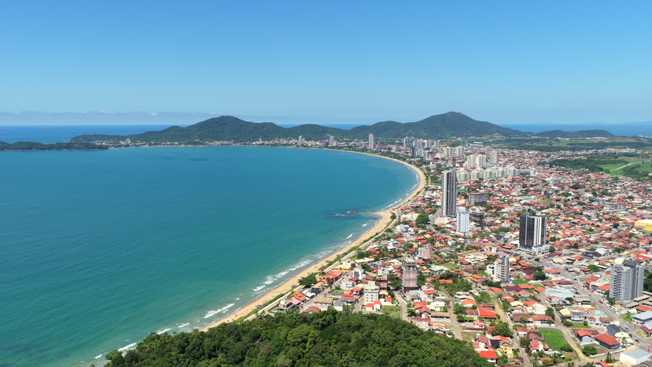 Penha attraverso una giungla lussureggiante in una giornata di sole, con vista sulla città, sull'oceano Atlantico e sulle colline distanti. Ripresa aerea frontale ad alta quota in una giornata di sole limpido.