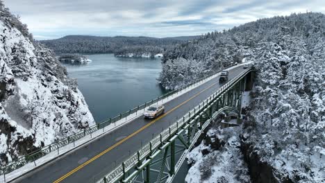 Toma-Aérea-Bajada-De-Autos-Que-Pasan-Por-Un-Puente-Con-Nieve-Por-Todas-Partes