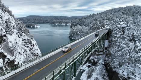 lowering aerial shot of cars passing over a bridge with snow everywhere