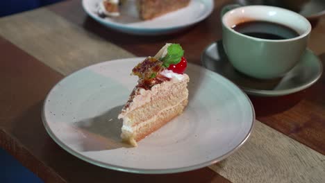 postre decorado con cereza, limón y azúcar para helado, junto con una taza de café servida en una mesa de madera en la cafetería