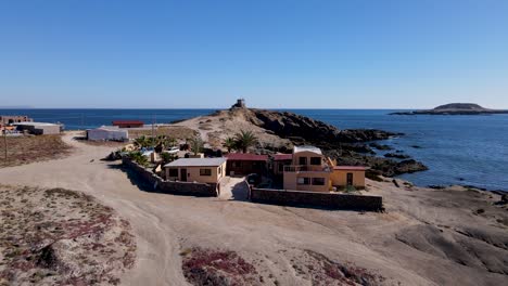 aerial dolly of coastal sea villa on rocky mexican beach by blue ocean water