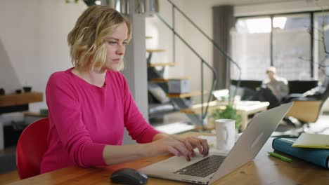 mujer rubia preocupada trabajando con una computadora portátil en casa