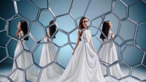 woman in white dress amidst hexagonal mirrors