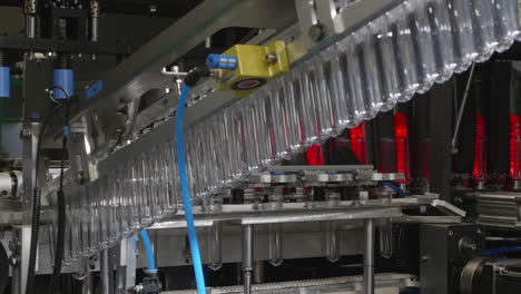 un vistazo a la línea de producción de botellas de plástico: las preformas de plástico para mascotas se trasladan a la máquina de calentamiento
