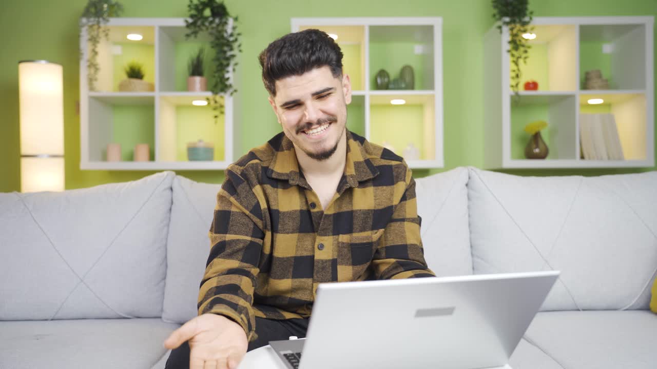 el joven está sorprendido y feliz con lo que ve en la computadora portátil.