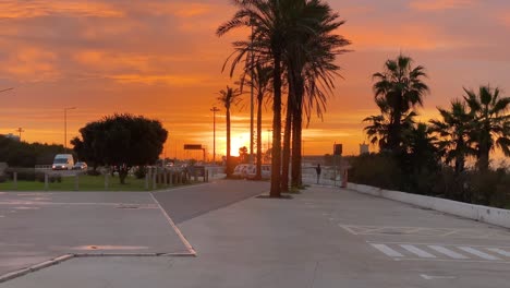 Incredible-beautiful-sunrise-sky-reflections-over-fort-Saint-Julian-at-Carcavelos-beach-near-Lisbon,-amazing-orange-teal-and-gray-tones,-man-seeing-the-waves