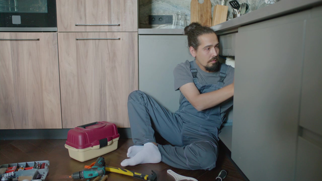Handyman Fixing Leaking Sink Drain with Hand Tools in Kitchen