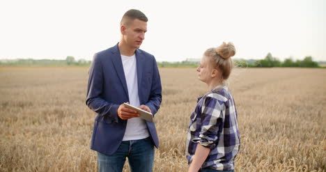 agriculture female and male farmers talking at wheat field during harvesting 11