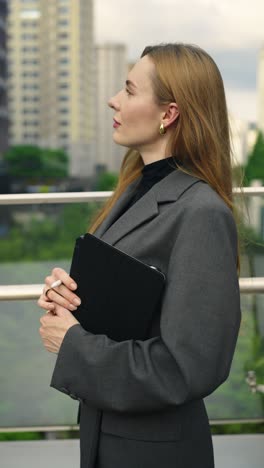 a businesswoman stands outdoors, first focused on her digital tablet, then gazing thoughtfully at surrounding office towers, inspired by a bright future