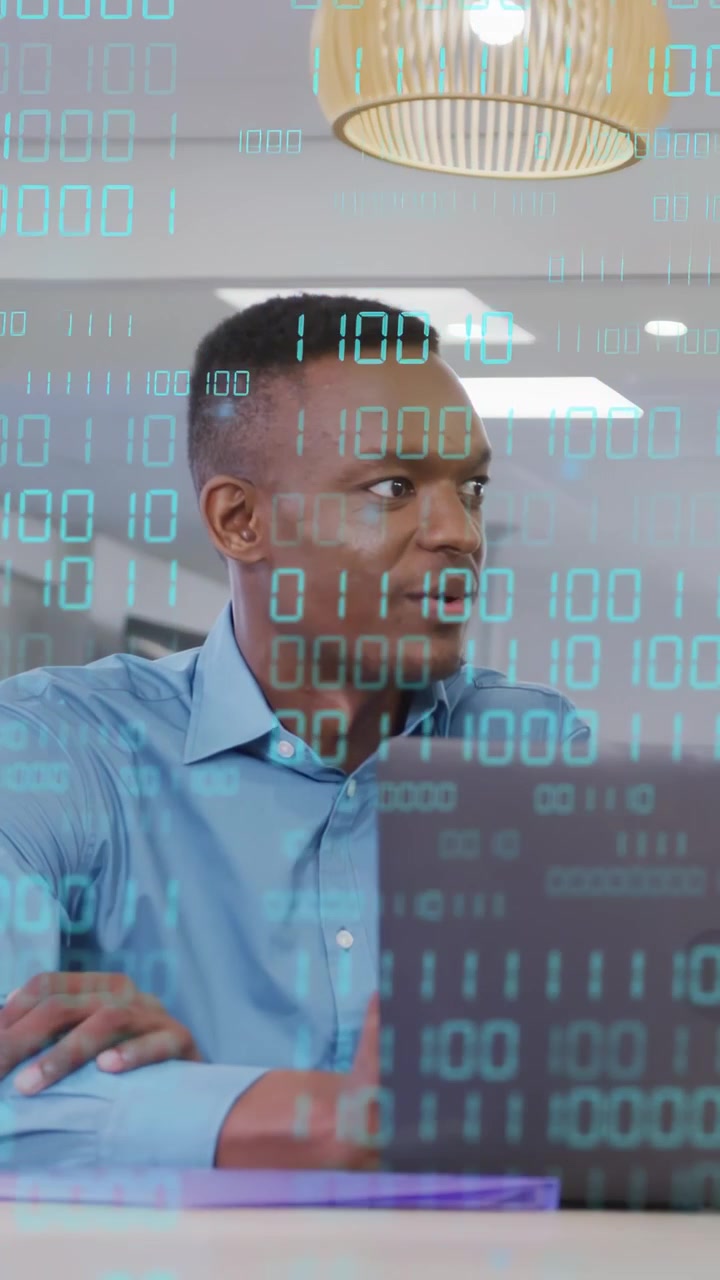 Vertikal video: IT-analytiker hører en samtale, snur seg til høyre, svarer mens binærkode strømmer over laptopen.