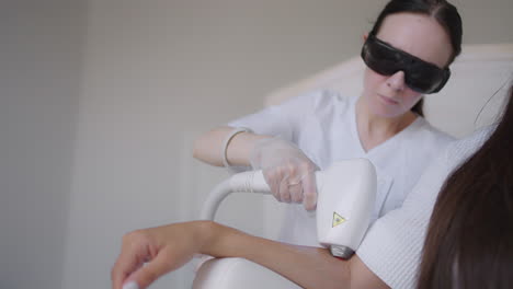 procedimiento de eliminación de vello en la mano. eliminación de vello láser en una cámara móvil de seguimiento láser de diodo. cosmetóloga mujer aplica gel de eliminación de vello láser en la mano femenina. concepto de cuidado corporal de fotoepilación.