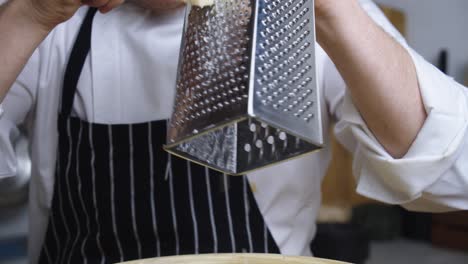 chef adds shredded cheese into deep bowl with caesar salad sauce