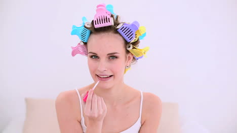 young model in hair rollers putting on lip gloss