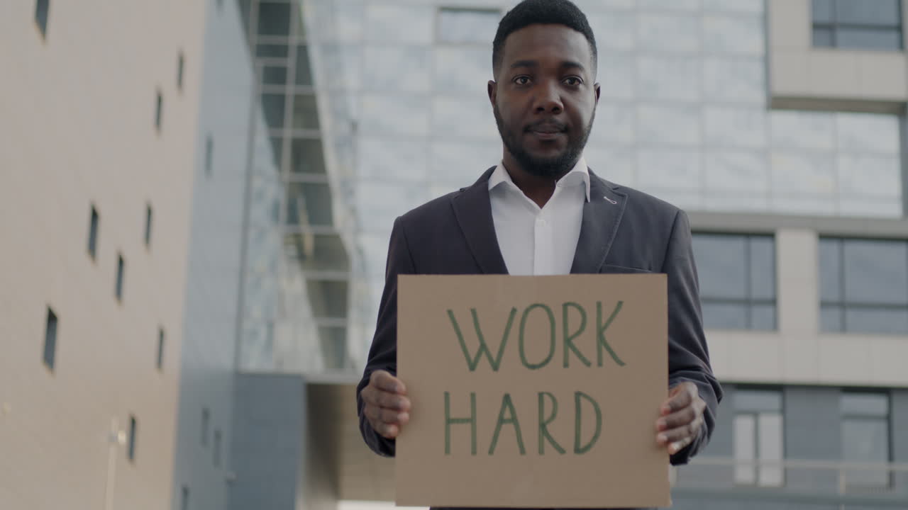 Man Holding Sign That Says "Work Hard"