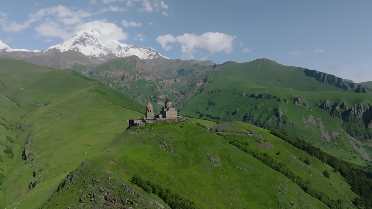 iglesia de la trinidad de gergeti en la cima de la colina en georgia - toma aérea de drones