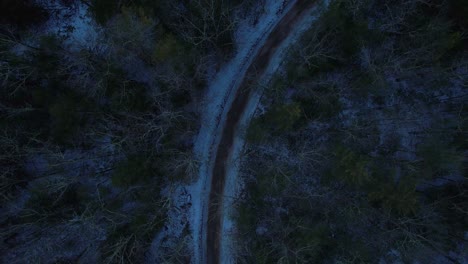 Smooth-nighttime-drone-footage-of-a-beautiful-road-through-a-snowy-winter-forest-in-the-Appalachian-mountains-during-winter-in-New-York's-Hudson-Valley-in-the-Catskill-Mountains-sub-range