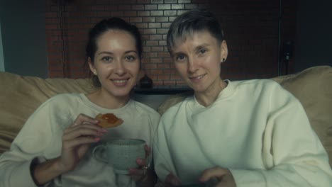 two women relaxing at home with tea and cookies