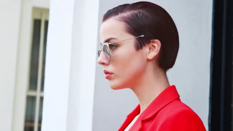 stylish woman wearing sunglasses standing outside city building