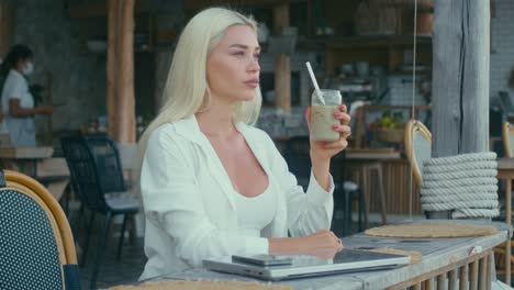 woman drinking iced coffee at an outdoor cafe