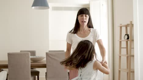 cheerful mom and daughter playing active games at home