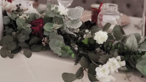 Gorgeous-head-table-flower-bouquet-laying-across-the-table-with-silverware-and-place-settings-set-out-behind-the-bouquet