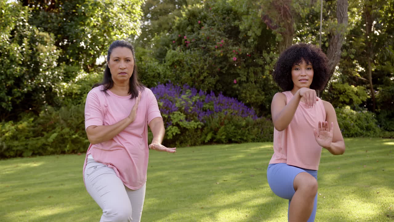 Practicing tai chi, mother and adult daughter enjoying outdoor exercise in park