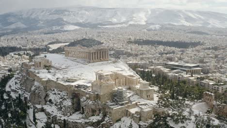 aerial view away from the snowy parthenon temple, winter in athens, greece - reverse, drone shot