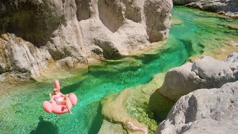 young woman floating down a lake on a flamingo