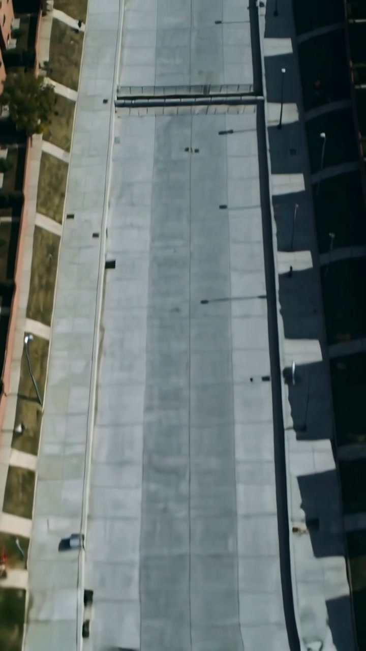 Vertical video: Drone launching then gliding over long concrete plaza at campus, mapping overpass
