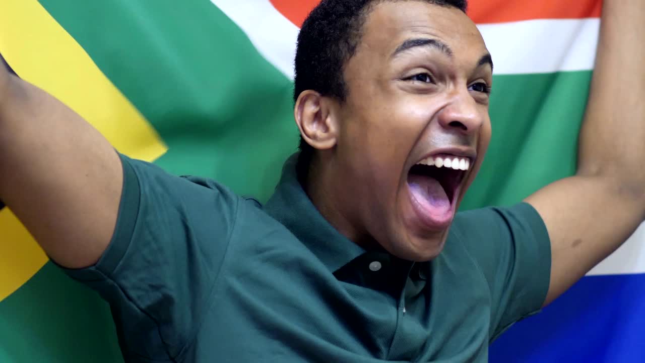 fanático sudafricano celebrando mientras sostiene la bandera de sudáfrica en cámara lenta