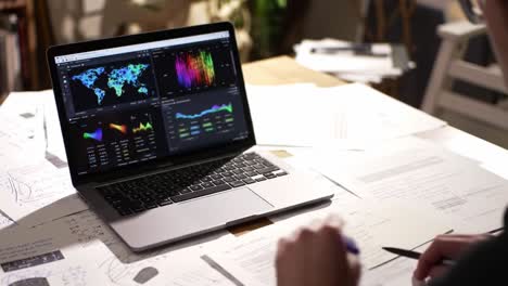 a focused analysis on data visualization: exploring interactive graphs and geographic mapping on a laptop surrounded by research notes and papers