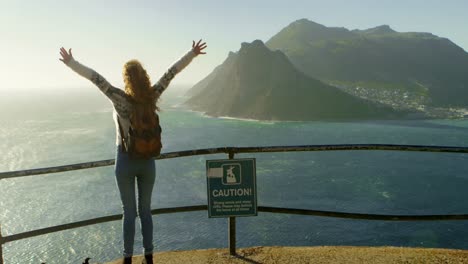 Woman-standing-with-arms-outstretched-near-a-sea-4k-