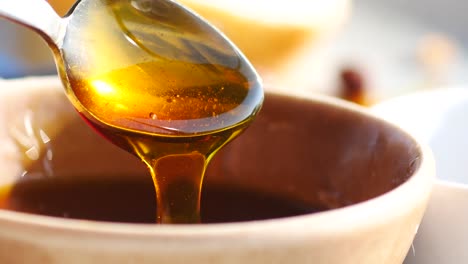 honey pouring from spoon into bowl