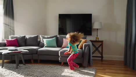 energetic young girl jumps with a pillow in a happy living room setting