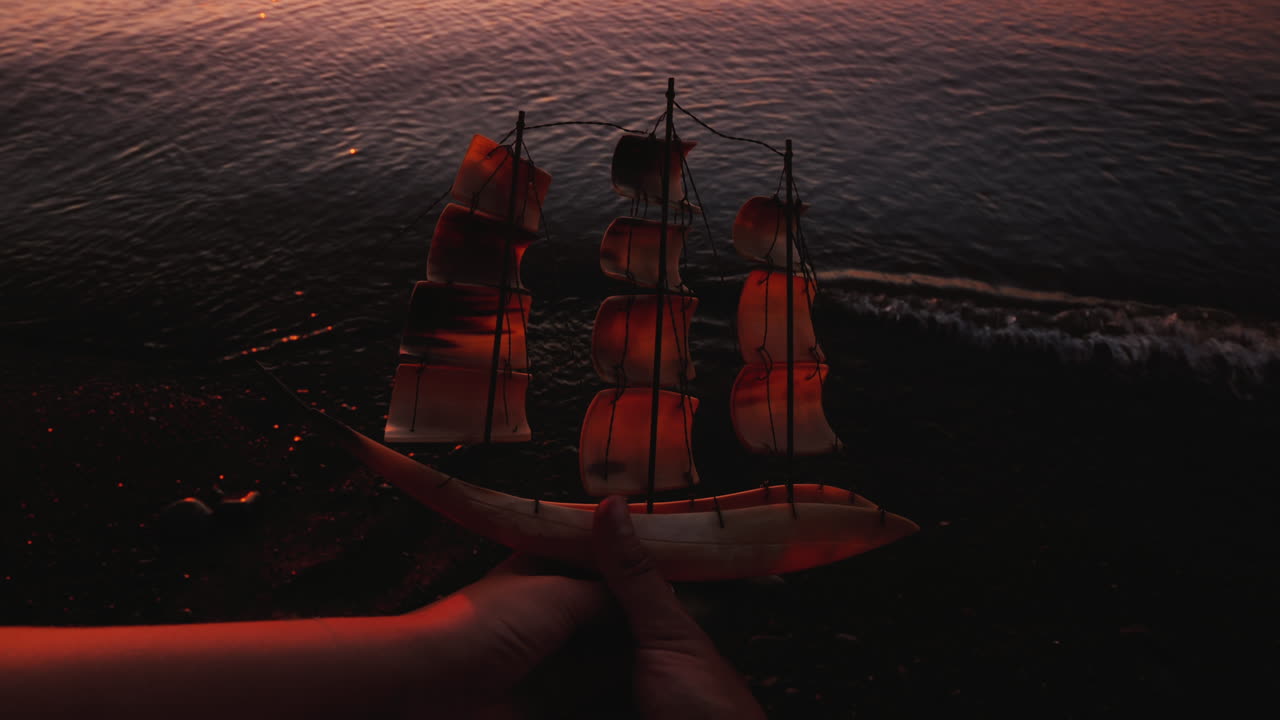 젊은 부부의 손은 바다와 일몰 c의 배경에 범선의 모델을 제기