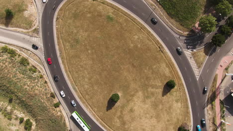Ellipse-shape-roundabout-in-Spain-with-vehicles-and-public-busses,-aerial-top-down-view